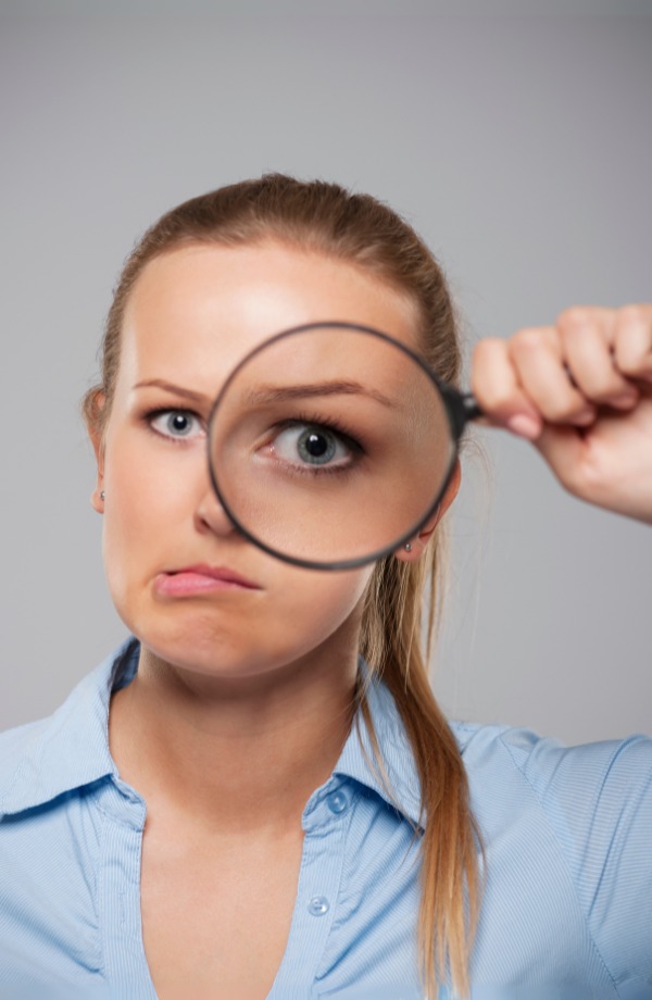 Persona mirando a través de una lupa, simbolizando la exploración y detección de creencias limitantes activas.