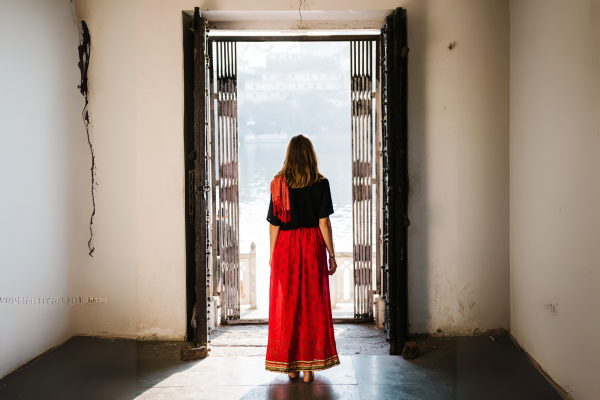 Mujer saliendo de una habitación hacia una puerta abierta, simbolizando bienestar emocional y equilibrio emocional como salida confiable